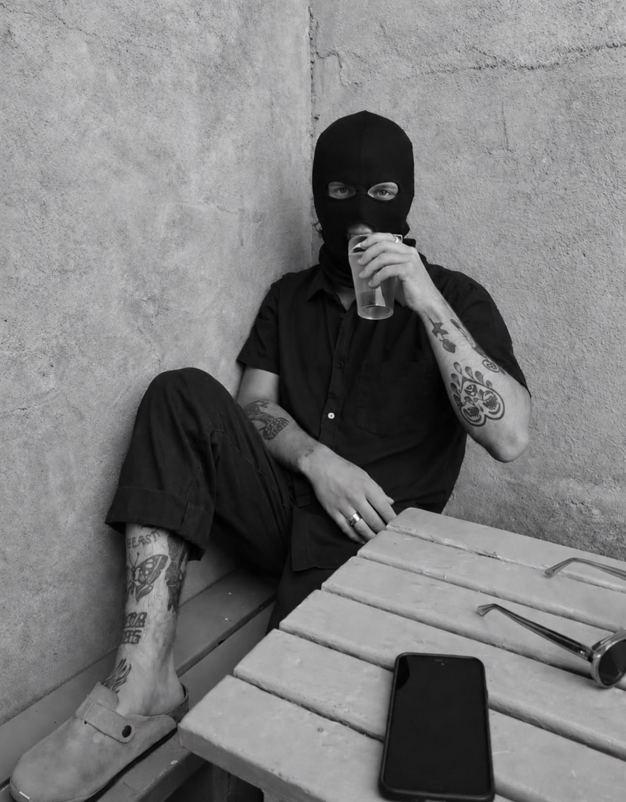 Masked portrait seated at a cafe table