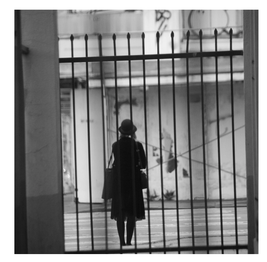 A solitary figure observed through an iron gate